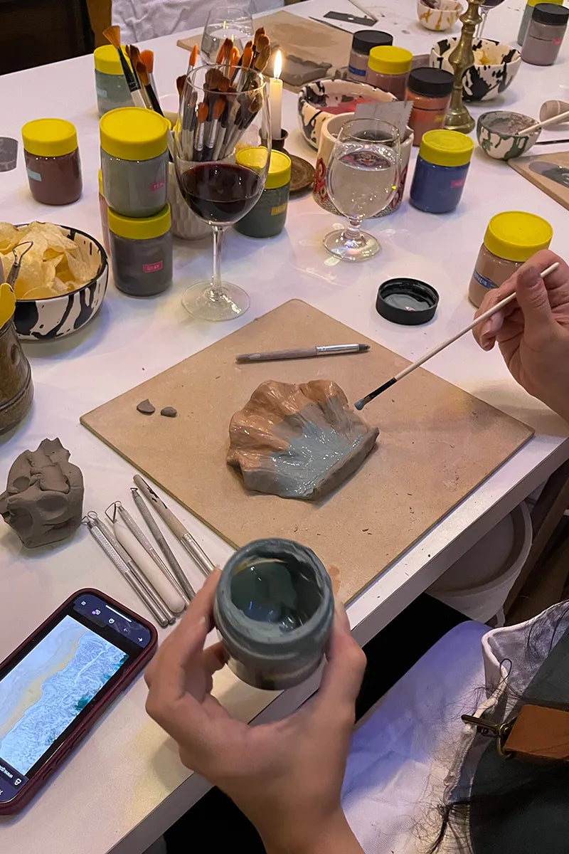 Student painting her pottery artwork at OWO’s wine & pottery class in Buenos Aires