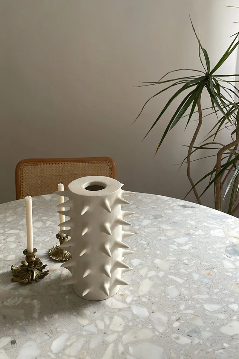 Handmade tall white ceramic vase with spike on top of a dinner table