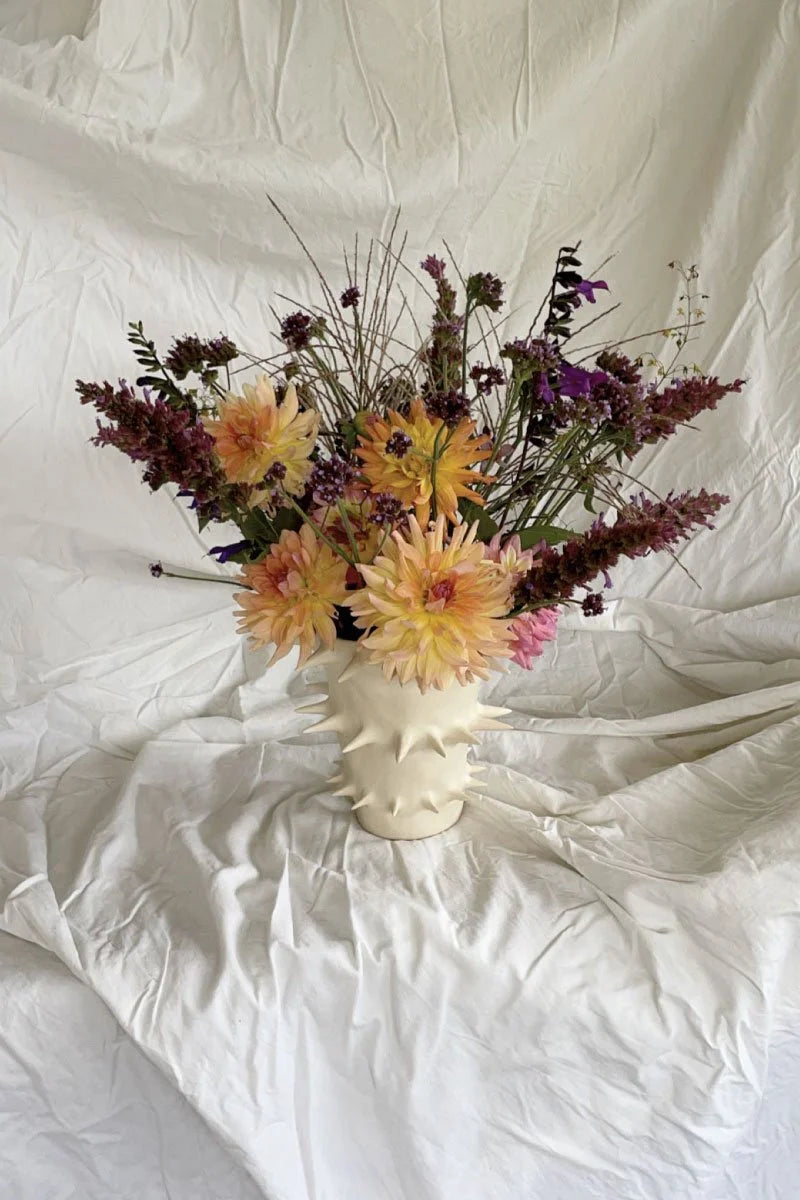 Handmade white ceramic flower vase filled with colorful blooms